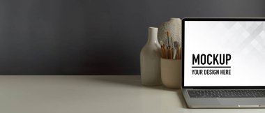 Çalışma alanını laptop, kırtasiye malzemesi, vazo ve ofis odasındaki kopyalama alanı ile kapat