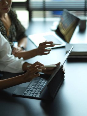 Toplantı masasında dijital tabletle çalışan iki kadının yan görüntüsü