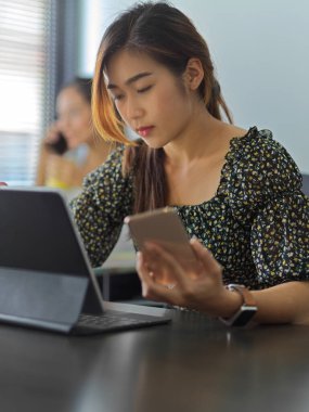 Ofiste akıllı telefon ve dijital tabletle çalışan kadın ofis çalışanının portresi