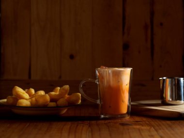 Thai usulü kahvaltıya yakından bak. Buzlu Tayland çayı ve ahşap masada kızarmış hamur çubukları olsun. 