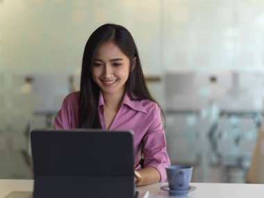 Modern ofis odasında dizüstü bilgisayarla çalışan kadın ofis çalışanının portresi.