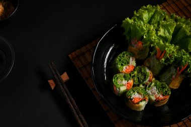 Asya aperatiflerinin üst görüntüsü, Vietnam börekleri koyu arkaplanda sos ile servis ediliyor.