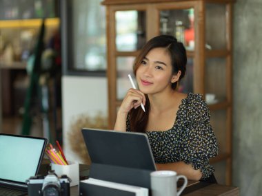 Dijital tabletle toplantı masasında çalışırken kameraya gülümseyen iş kadınının portresi