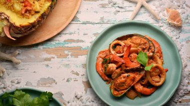 Tahta masadaki yeşil seramik tabakta deniz mahsulleri kızartılmış köri tozu, Tayland yemeği.