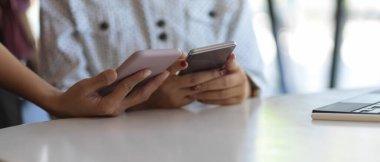 Ofisteki işlerinde danışmanlık yapmak için iki akıllı telefonu tutan ellerin yakın görüntüsü