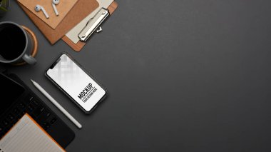 Akıllı telefon, kırtasiye malzemesi, malzeme ve gri masadaki alanı kopyalayan çalışma alanının en üst görünümü