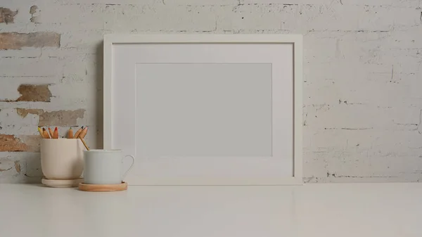 Close up view of white desk with mock up frame, stationery, cup and copy space in living room