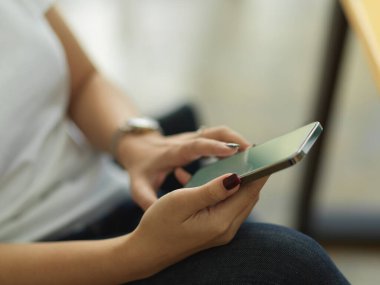 Ofiste otururken akıllı telefon kullanan kadınların yan görüntüsü