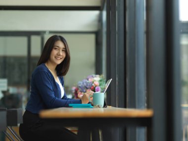 Kafede ödev yaparken kameraya gülümseyen kadın üniversite öğrencisinin portresi