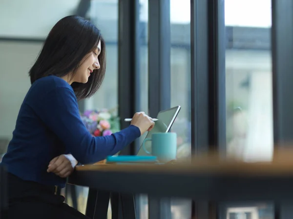 女性学生の側のビューは カフェで木製のバーにタブレットで課題を行う — ストック写真