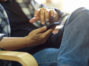 Sandalyede rahatça otururken akıllı telefon kullanan bir erkeğin yan görüntüsü 