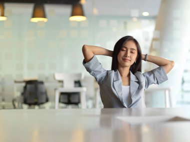 İş kadını portresi, modern toplantı odasında rahat bir şekilde uzanıp ofis işlerine kısa bir süre ara veriyor.