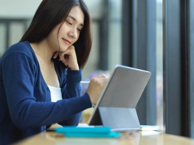 Dijital tablet ve kafedeki kırtasiye ile ödev yapan kız öğrencinin yakın görüntüsü