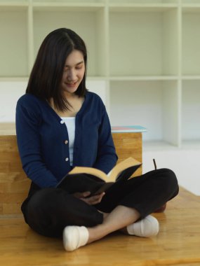 Okuma köşesinde merdivenlerde oturmuş kitap okuyan kız öğrencinin portresi.