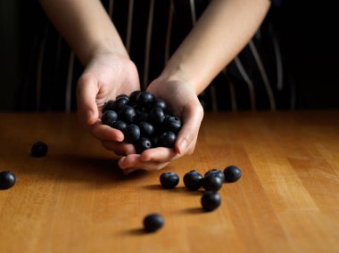 Kadın ellerinin ahşap masada bir sürü yaban mersini tutmasını yakından izleyin. 