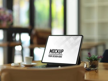 Tablet, klavye, gözlük, aksesuar ve bardakla kesilmiş ahşap masa resmi.