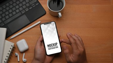 Tahta masada akıllı telefon kullanan erkeklerin üst görünümü, kırpma yolunu da içerir