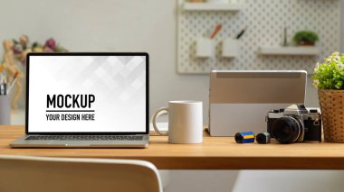 Ofis odasının arka planda ofis malzemeleriyle dizüstü bilgisayarlı, fincanlı ve kameralı görüntüleri.