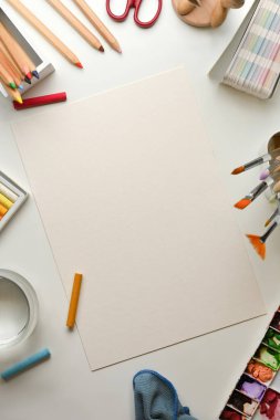 Sanatçı çalışma alanının yaratıcı düz yatağı beyaz masa üzerinde kağıt ve boya araçları ile