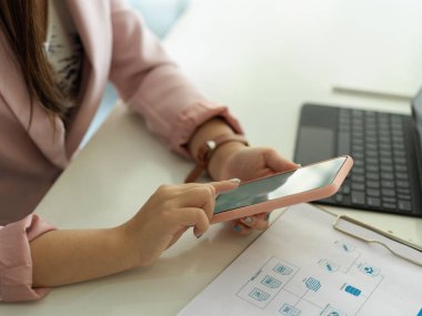 Dijital tablet ve evrak işleriyle uğraşırken akıllı telefon kullanan iş kadınının yan görünümü