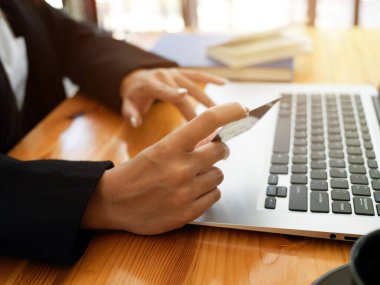 Kredi kartı tutan ve online ödemeye dizüstü bilgisayarda yazan bir kadının yan görüntüsü 