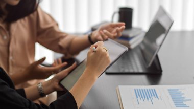 Dijital tabletle çalışan ve işlerini tartışan iki iş kadınının yan görünümü 