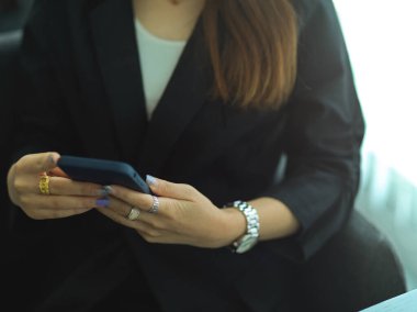 Ofiste otururken akıllı telefon kullanan iş kadınının el görüntüsünü kapat