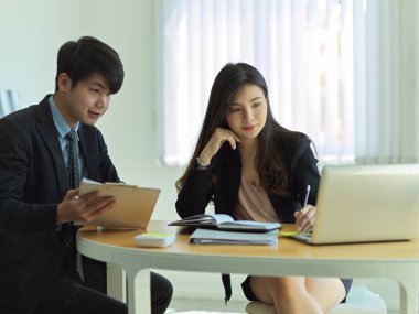 İş adamlarının portreleri ofis odasında dizüstü bilgisayar ve evrak işleriyle ilgili beyin fırtınası yapıyorlar.