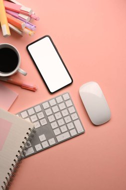 Akıllı telefon, bilgisayar klavyesi, fare ve kırtasiyeli pembe yaratıcı çalışma alanının üst görünümü