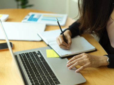 Ofis odasında dizüstü bilgisayarla çalışırken iş kadını el yazısı çizelgesinin yan görüntüsü