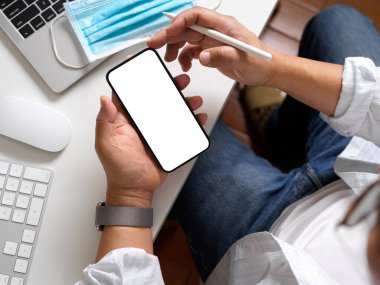 İş adamının akıllı telefon kullanırken ve iş yerinde elinde Stylus kalem tutarken çekilen fotoğrafı. 