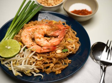 Karıştırılmış karidesli Tayland eriştesi limonlu, fasulyeli ve soğanlı, seramik tabakta Pad Thai soslu.