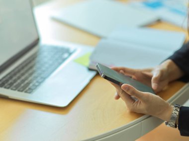 Bilgisayarlı ve malzemeli akıllı telefon kullanan işadamlarının yan görüntüsü