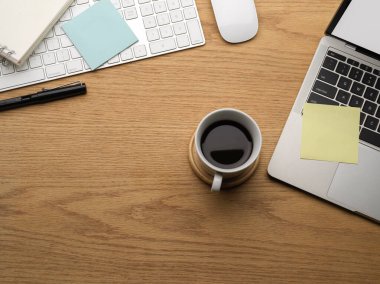 Fotokopi alanı, dizüstü bilgisayarı, kahve fincanı ve kırtasiyesi olan ahşap masa manzarası.