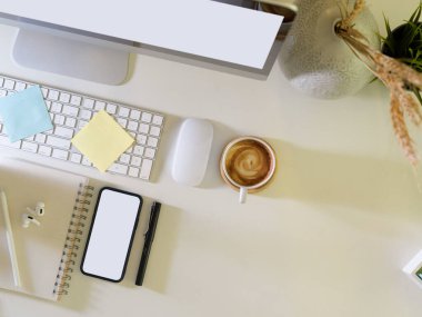 Bilgisayar, akıllı telefon, kırtasiye, kahve fincanı ve fotokopi alanı olan yaratıcı düz çalışma alanının üst görünümü, kırpma yolu