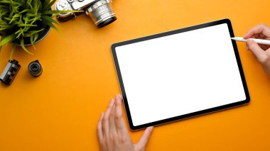 Stylus kalemle kadın elinin en üst görünümü dijital tablet kullanarak kamera ve saksı ile çalışma alanı, kırpma yolu