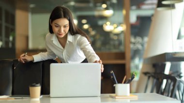 Close up view of female entrepreneur working with laptop and office supplies on office desk while standing