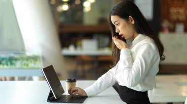 Side view of female offie worker shocked while working with digital tablet in office room
