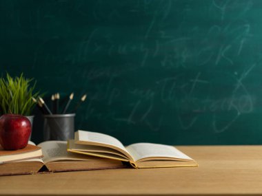 Cropped shot of school elements on wooden table with copy space and chalkboard wall background