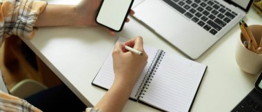 Boş deftere yazılan serbest çalışan kadın el yazısı ve çalışma alanındaki akıllı telefonu taklit ederek.