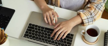 Scott ceketli kadın Freelander 'ın üst görüntüsü. Ev ofisinin klavyesinde dizüstü bilgisayarda yazı yazması.