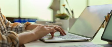 Scott ceketli kadın serbest çalışanın ev ofisinin klavyesinde dizüstü bilgisayarda daktilo kullanışının yan görüntüsü