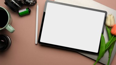 Dijital tablet, laptop, lale çiçeği, kamera ve kahve fincanı ile pembe yaratıcı çalışma alanı, kırpma yolu