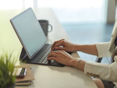 İş kadını ellerinin ofis masasındaki tablet klavyeye yazı yazışının yan görüntüsü