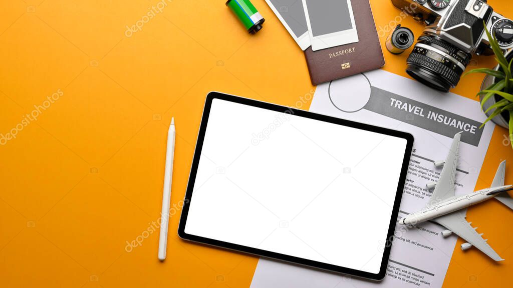 Top view of creative flat lay photo of yellow table with digital tablet, travel insurance form, passport, camera, and copy space, clipping path
