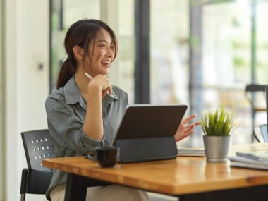 Modern ofis odasında çalışırken meslektaşıyla konuşan kadın ofis çalışanının portresi.