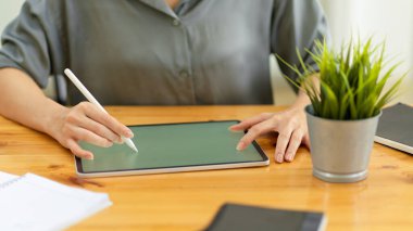Stylus kalemle dijital tablet üzerinde çalışan kadını yakın plan ofis malzemeleri ile ahşap ofis masasında