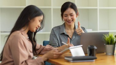 Ofis odasında birlikte çalışırken kadın işçinin yarım boy portreleri iş arkadaşına baş parmak işareti yapıyor.