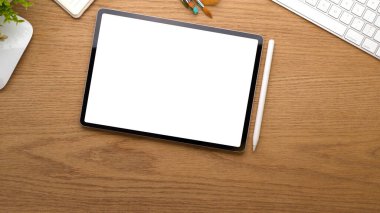 Dijital tabletli ahşap tablonun en üst görünümü ana ofis odasında kırpma yolu, stilus ve malzemeler içerir