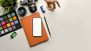 Akıllı telefon, kamera, renk denetleyici ve kopyalama alanı olan fotoğrafçı çalışma alanının üst görünümü, kırpma yolu